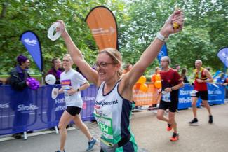 Woman representing Independent Age reaches the finish line of the Manchester Half Marathon