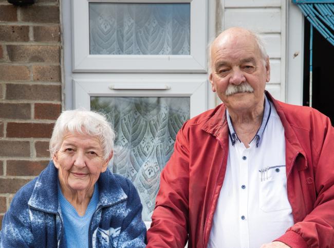 Older couple standing in front of house