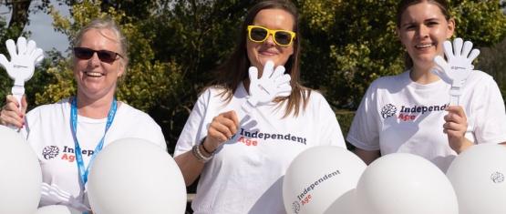 Three Independent Age staff members at fundraising event with white balloons