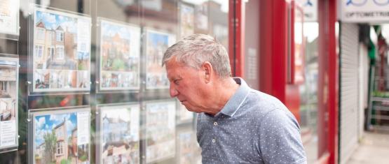Older man looking at properties in estate agent window