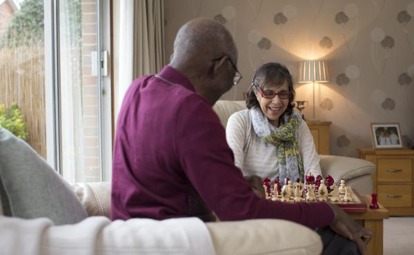 An older woman and man play chess together