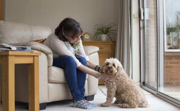 A woman sits at home, petting her dog