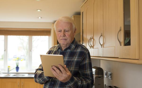 Man in kitchen reading a tablet