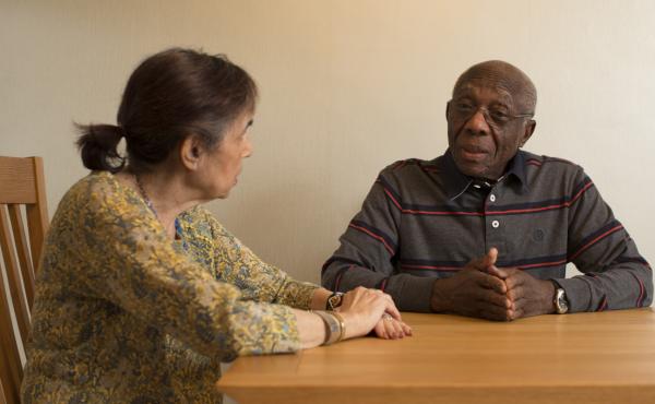 An older man and woman sit at a table having a conversation