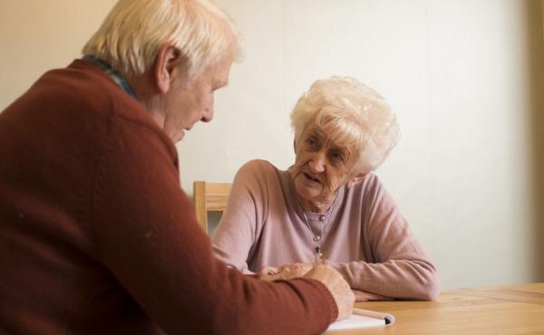 An older couple sit at a table having a discussion