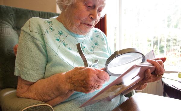Woman using magnifying glass to read