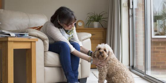 A woman sits at home, petting her dog