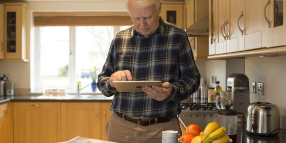 A man in a kitchen reading a tablet