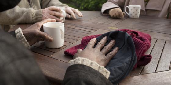 A group of older people drink tea seated outdoors