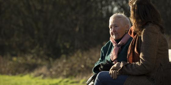 Older and younger woman talking on a park bench