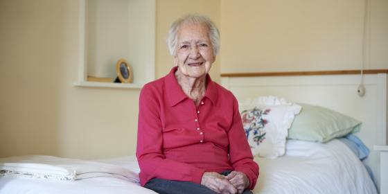 An older woman on her bed smiling