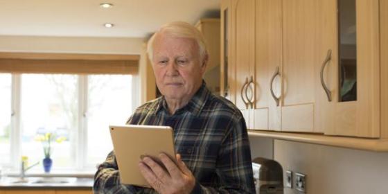 Man in kitchen reading a tablet
