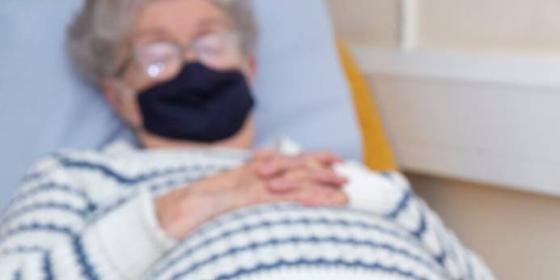 Woman wearing face mask lying in hospital bed
