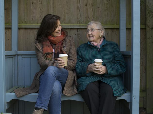 Two women sit in the garden talking 