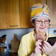 An older woman using a smartphone in her kitchen