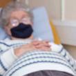 Woman wearing face mask lying in hospital bed