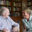 Older man and paid carer talking in care home