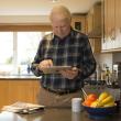 A man in a kitchen reading a tablet