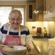 An older woman makes a cake